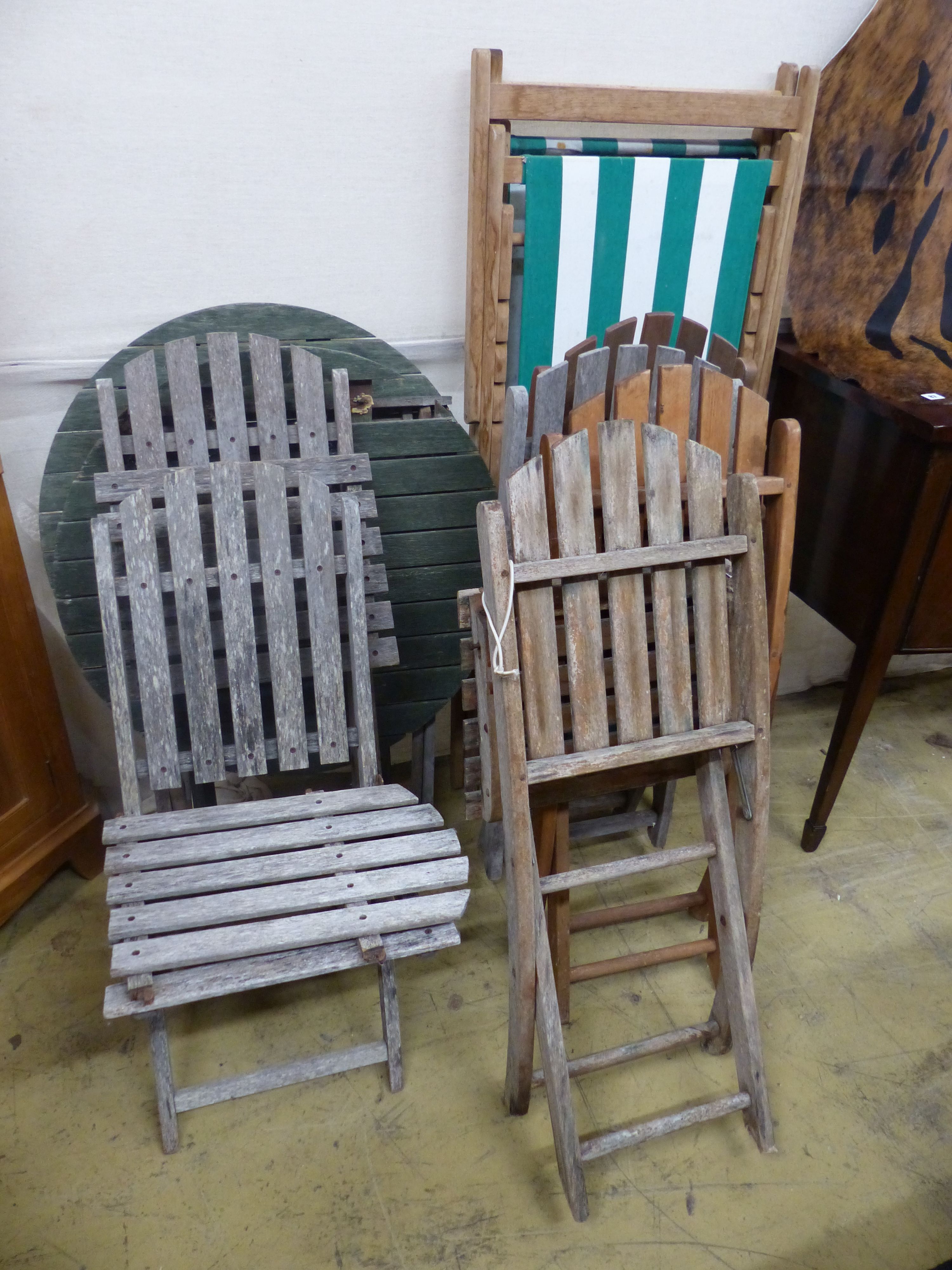 Six assorted weathered teak folding garden chairs, two similar circular tables and a deck chair